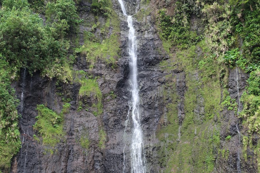 Tall waterfall surrounded by green tropical vegetation